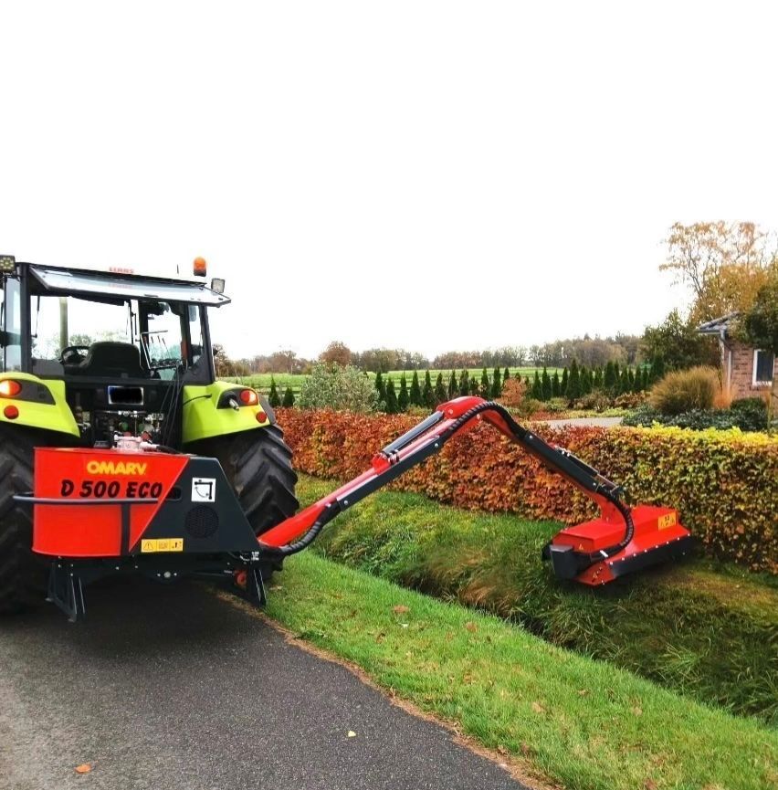 Ein Traktor mit einem daran befestigten Mäher steht am Straßenrand