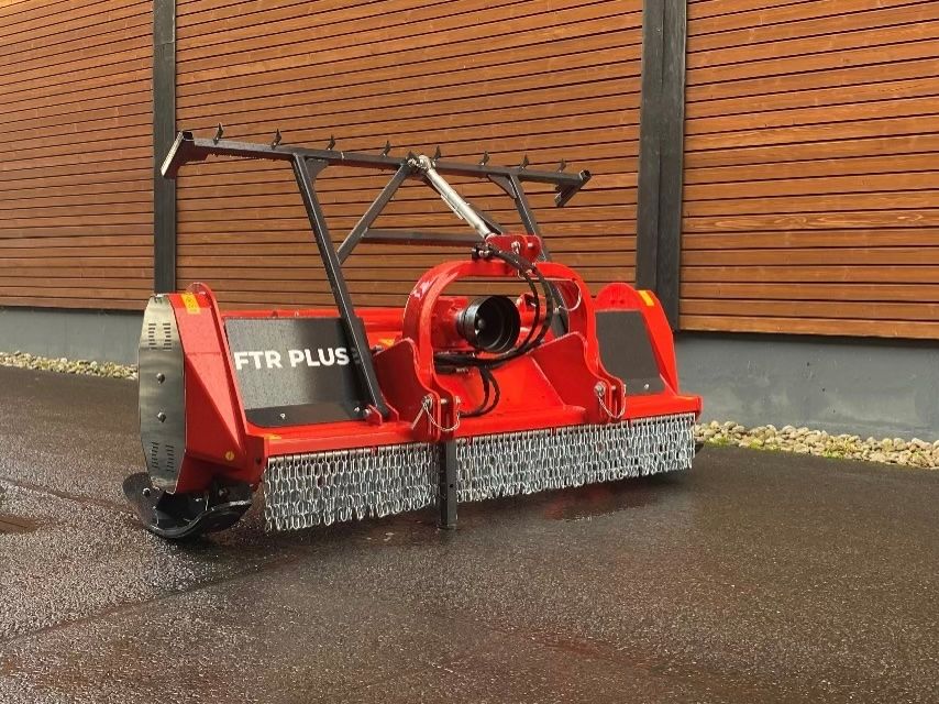 Ein roter Traktor steht vor einem Holzgebäude.