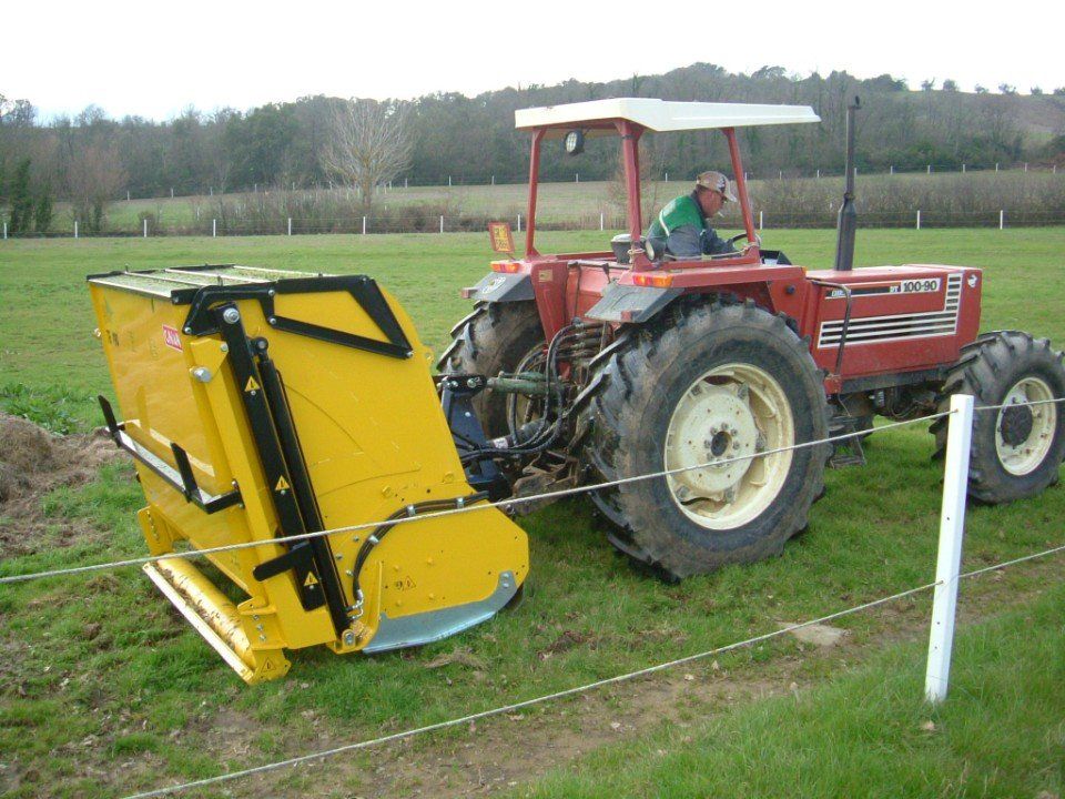 Ein Mann fährt einen roten Traktor auf einer Wiese