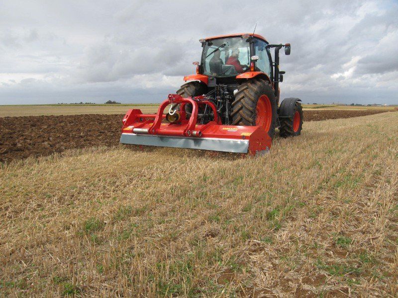 Ein rot-orangefarbener Traktor pflügt ein Feld