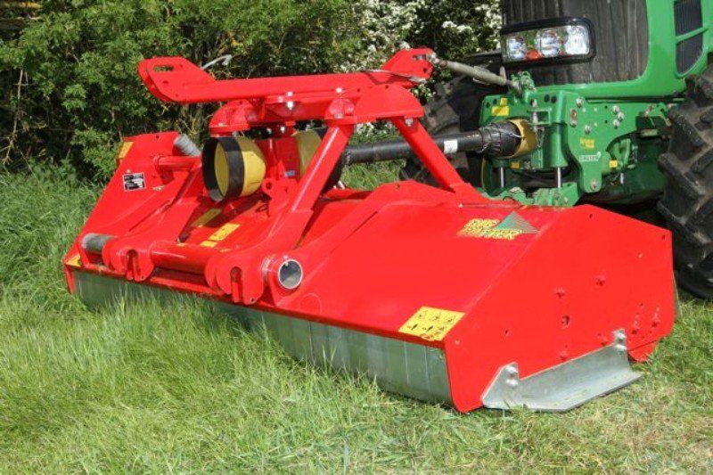 Ein grüner Traktor mit einem daran montierten roten Mäher.