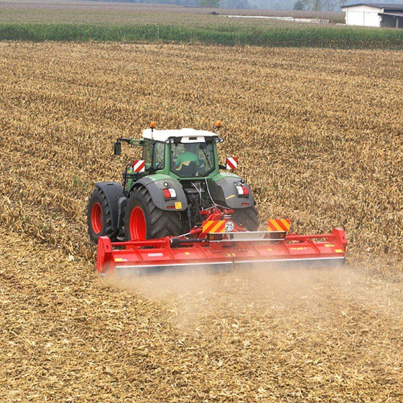 Ein grün-roter Traktor pflügt ein Feld