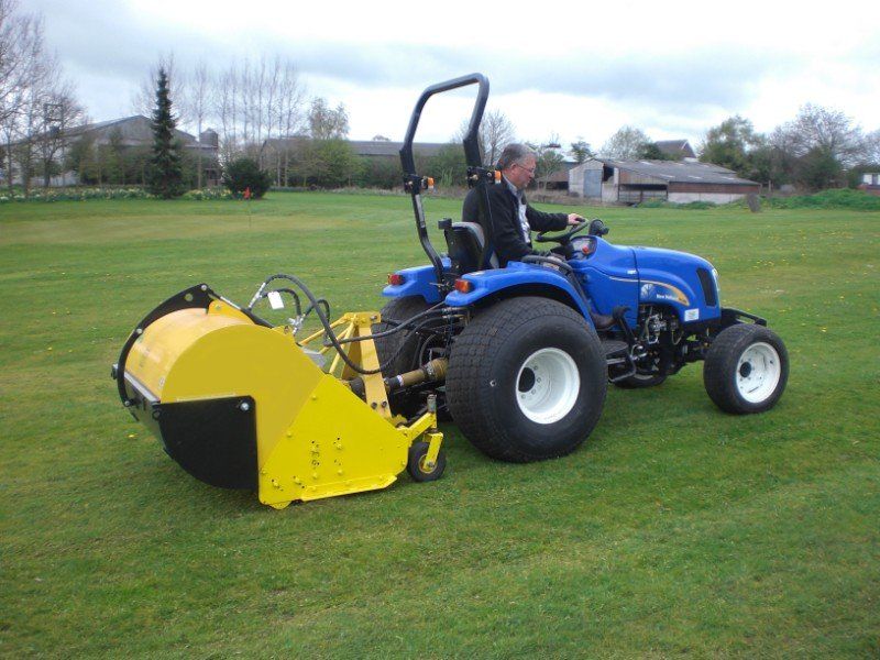 Ein Mann fährt einen blauen Traktor auf einem üppigen grünen Feld