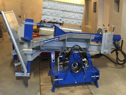 Eine blau-silberne Maschine steht auf einem Holzboden in einer Garage.