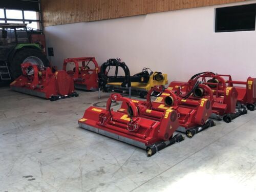 In einer Garage steht eine Reihe roter und gelber Traktoren.