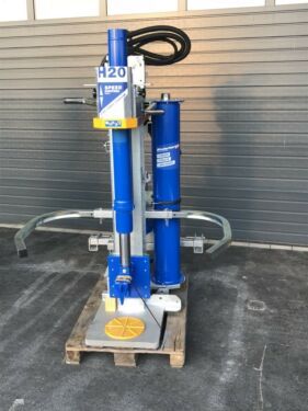 Eine blaue Maschine steht auf einer Palette vor einem Gebäude.