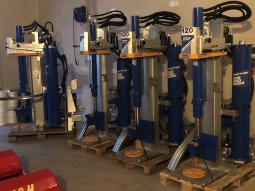 Eine Reihe blauer und silberner Maschinen stehen auf Paletten in einem Raum.