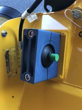 An einem gelben Fahrzeug ist eine blaue Box mit grünem Knopf befestigt