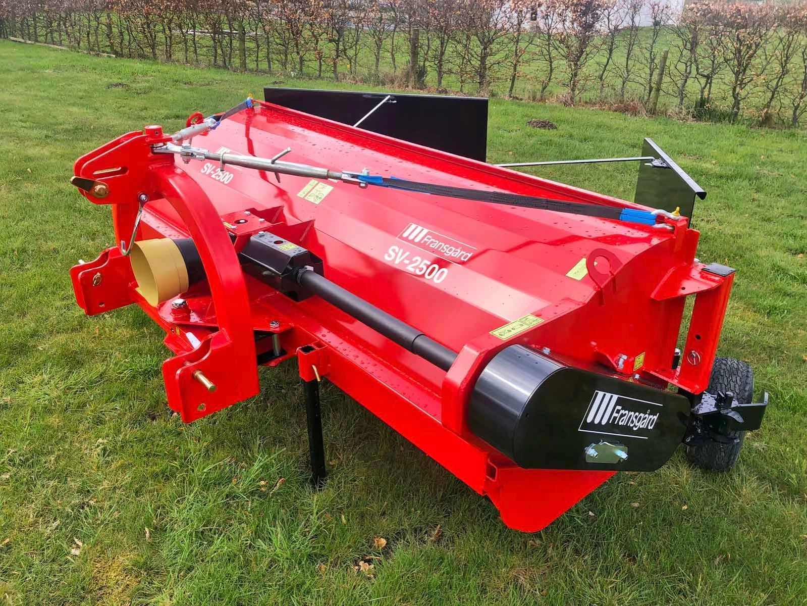 Ein roter Traktor steht auf einer Wiese.