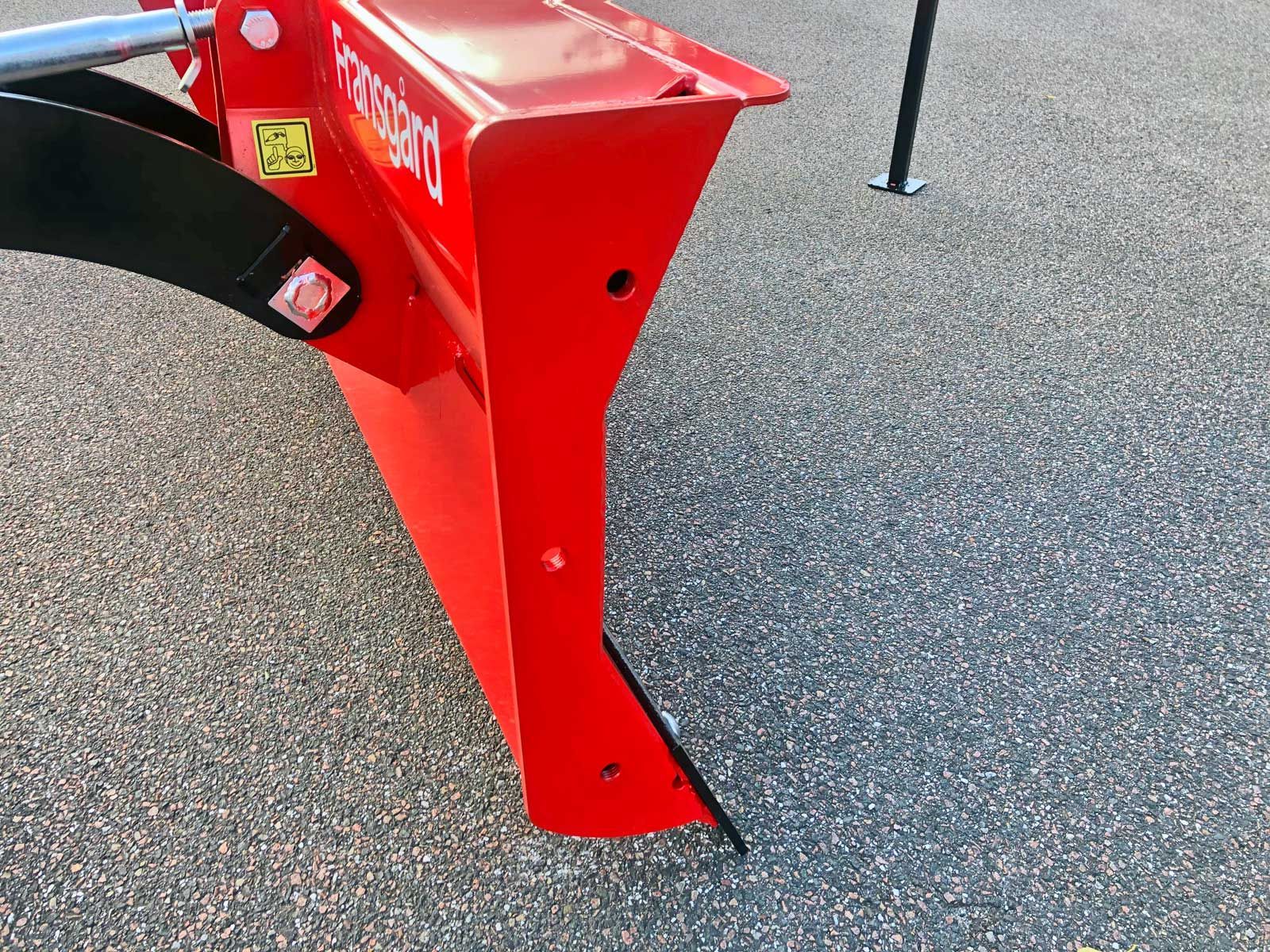 Ein roter Traktor steht auf einer Schotterstraße