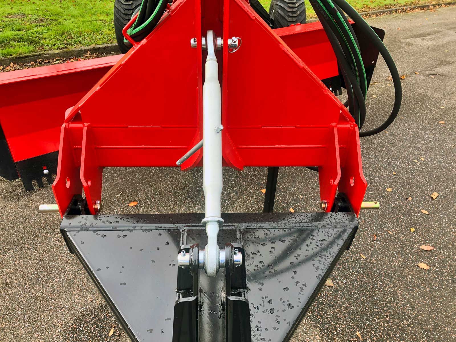 Ein rot-schwarzer Traktor steht am Straßenrand