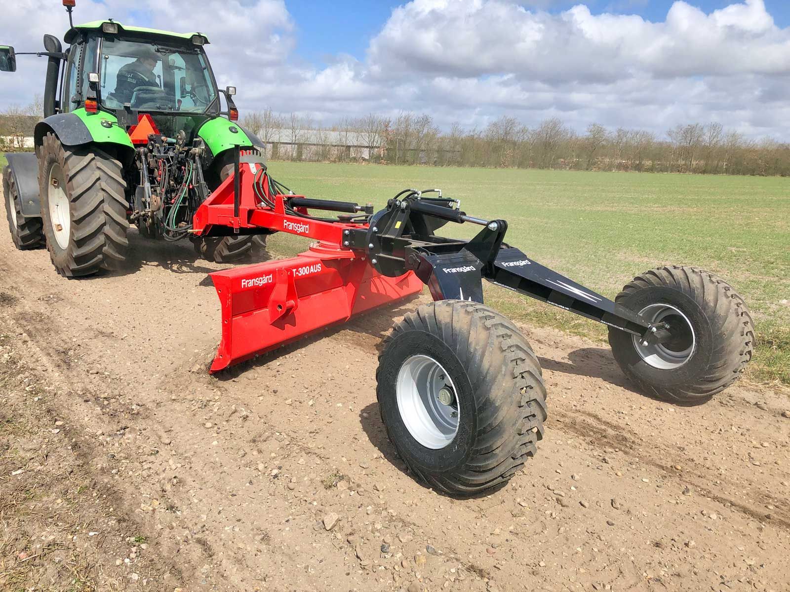 Ein grün-schwarzer Traktor steht auf einem Feldweg.