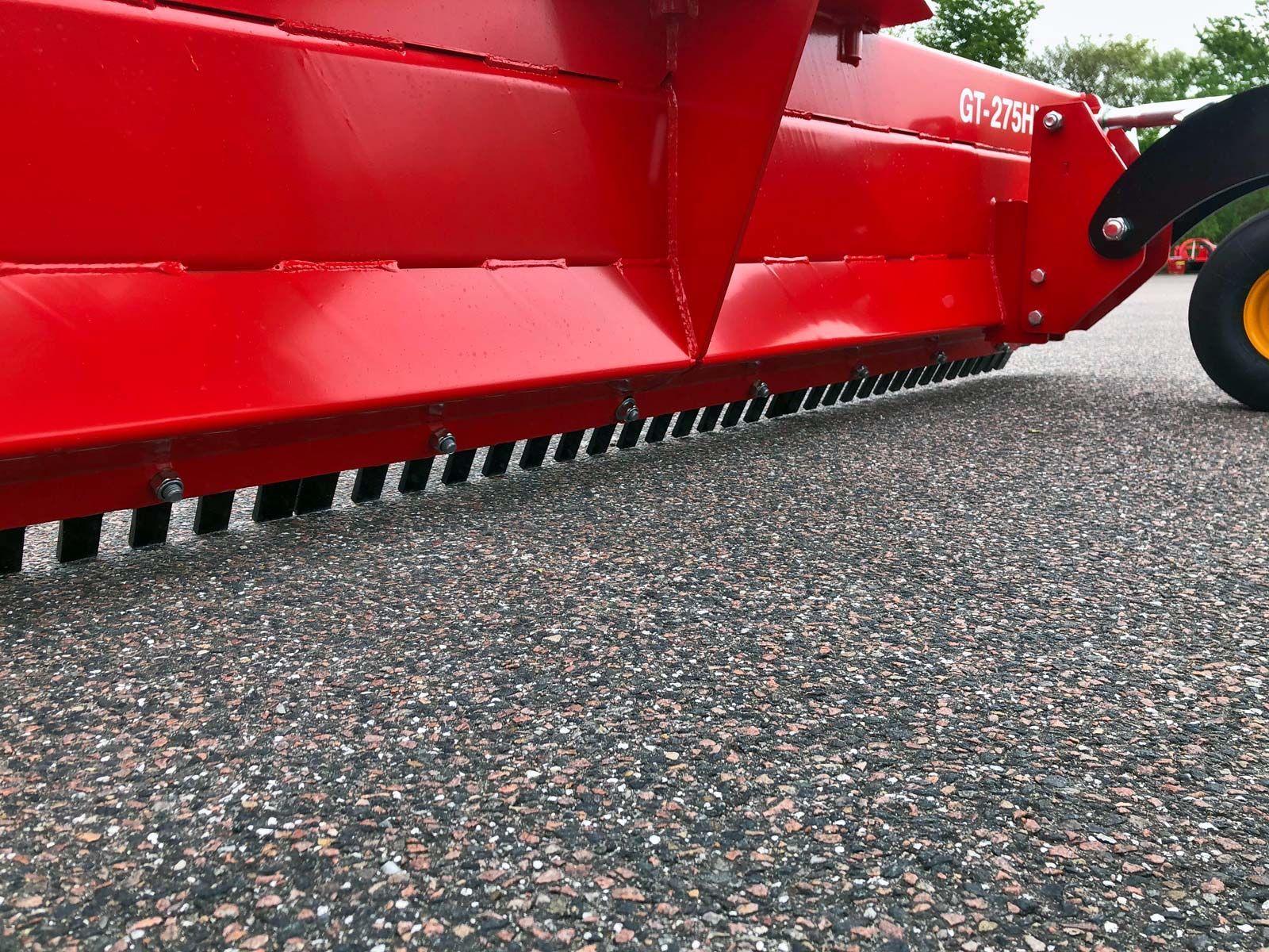 Ein roter Traktor parkt auf einer Schotterstraße.