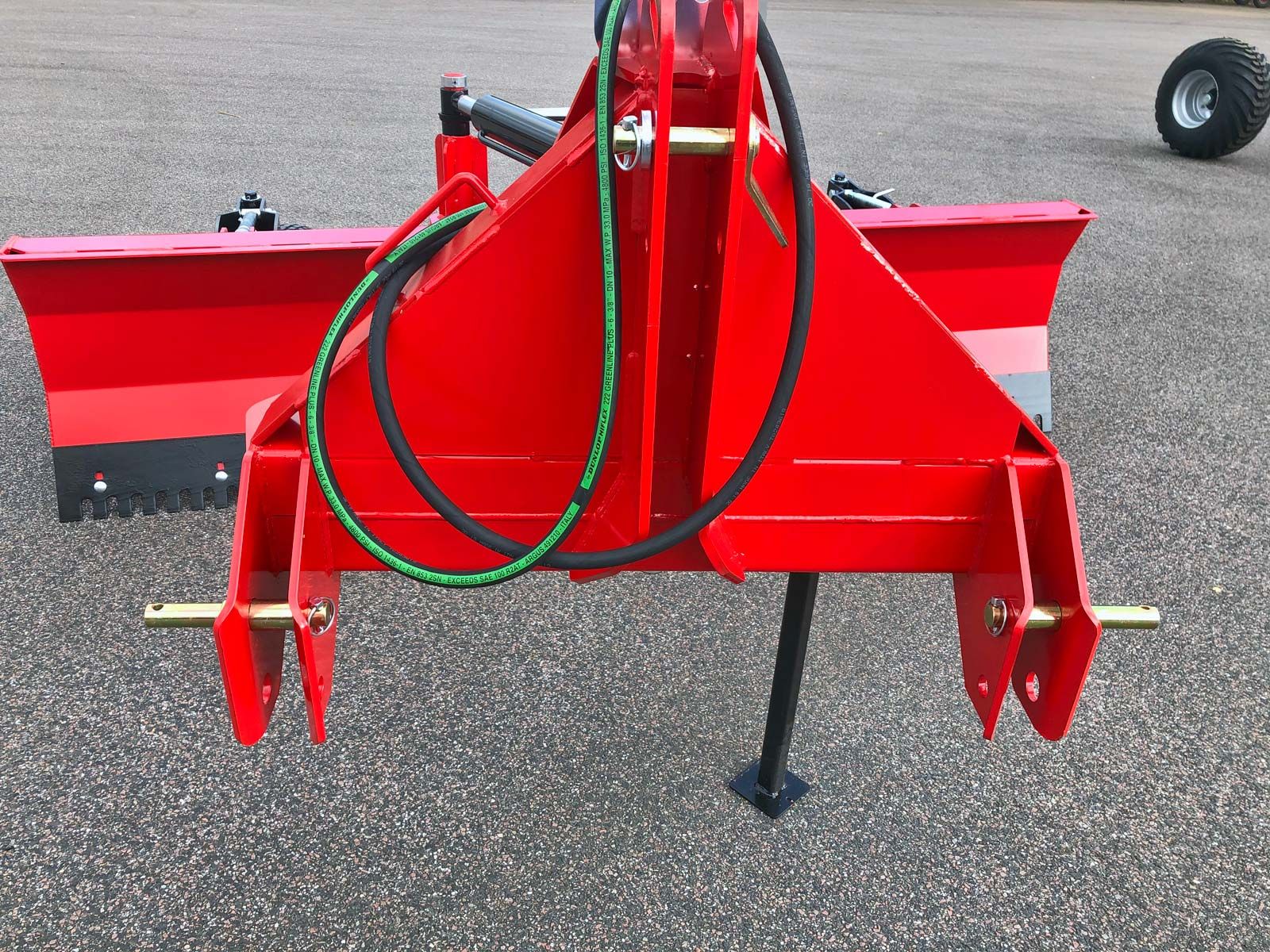 Ein roter Traktor mit einem daran befestigten grünen Schlauch