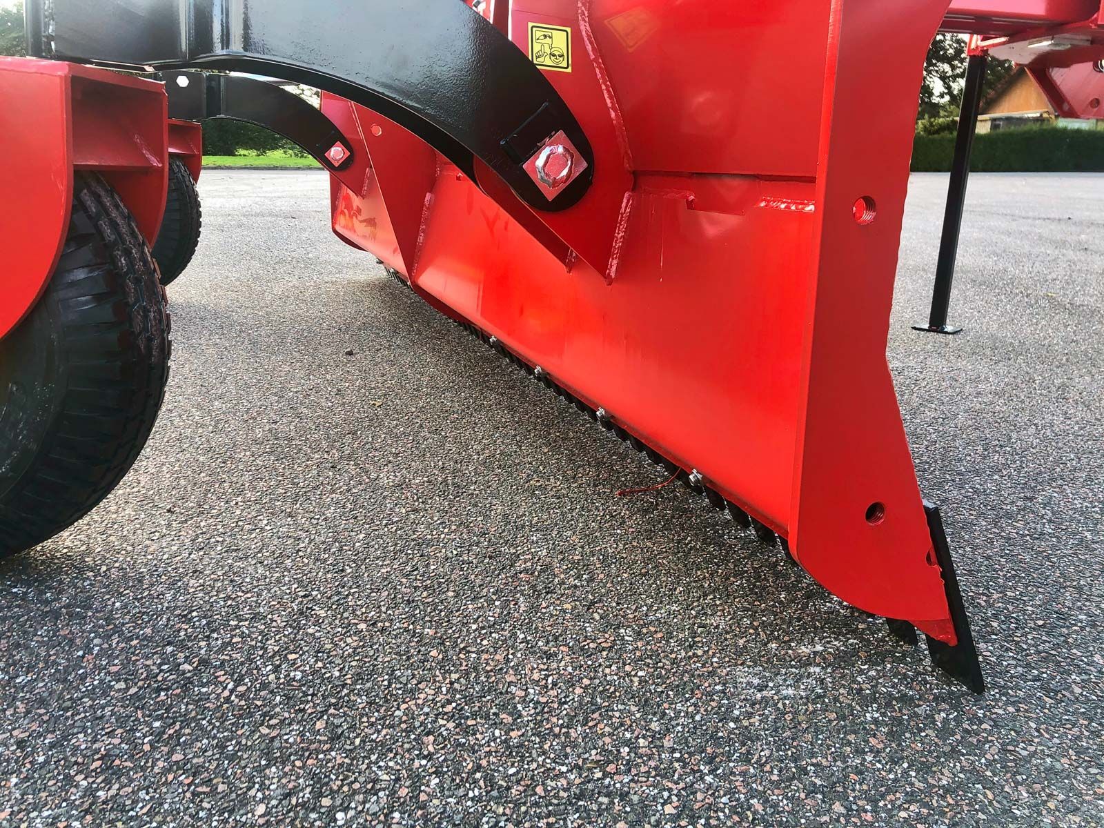 Ein roter Traktor steht auf einer Schotterstraße