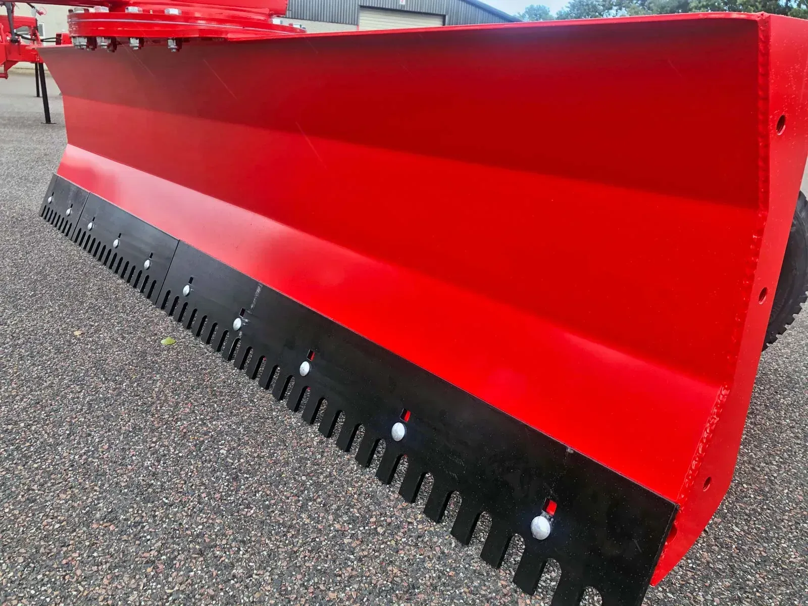 Auf dem Boden liegt ein roter Schneepflug mit schwarzen Zähnen.