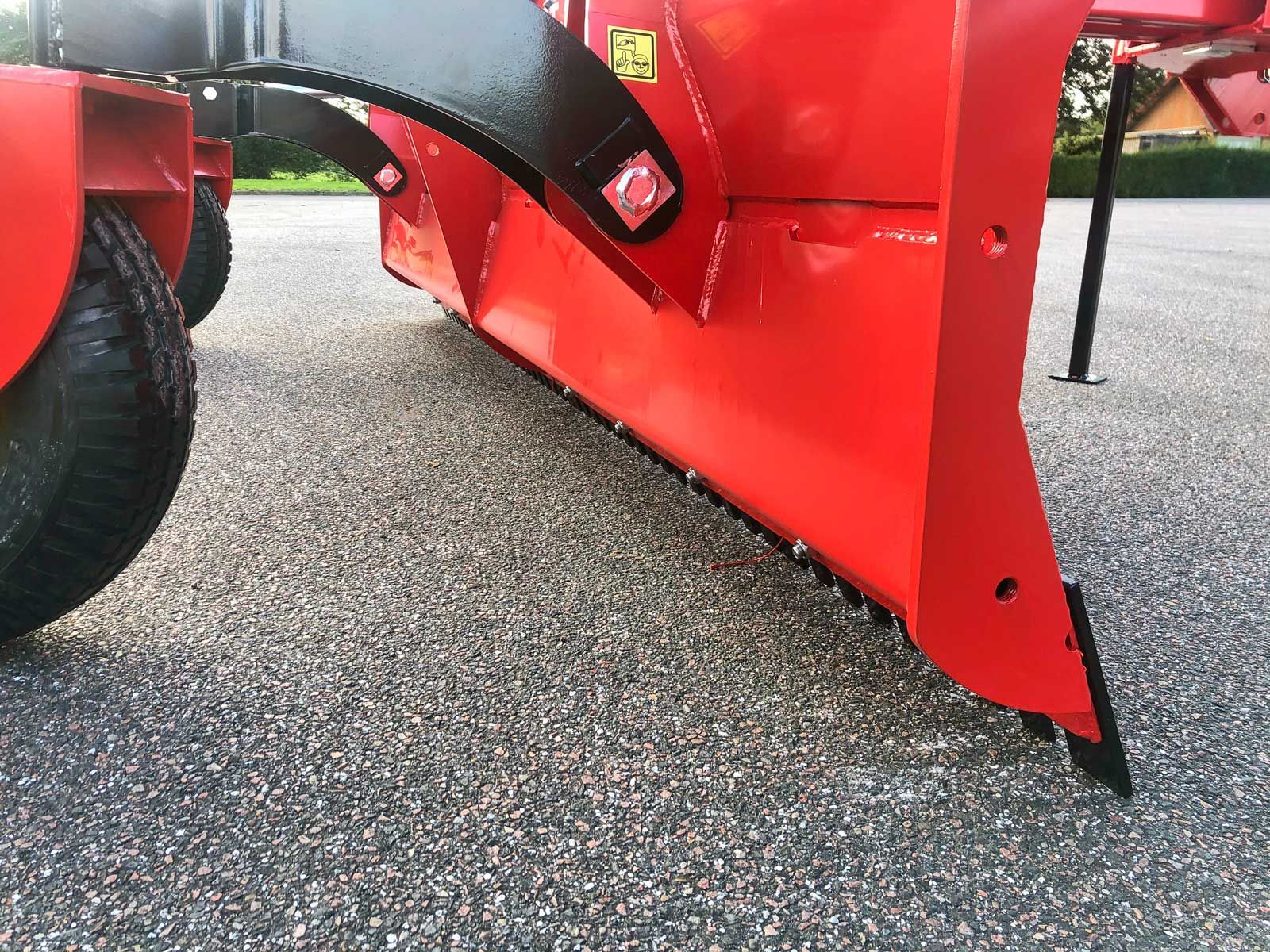 Ein roter Traktor steht auf einer Schotterstraße