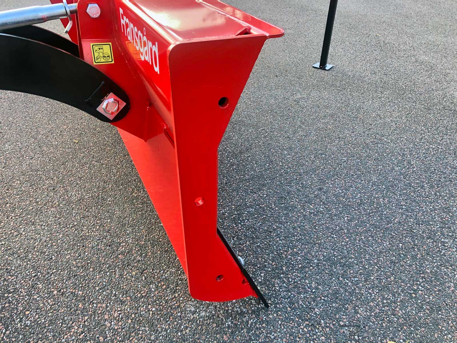 Ein roter Traktor steht auf einer Schotterstraße