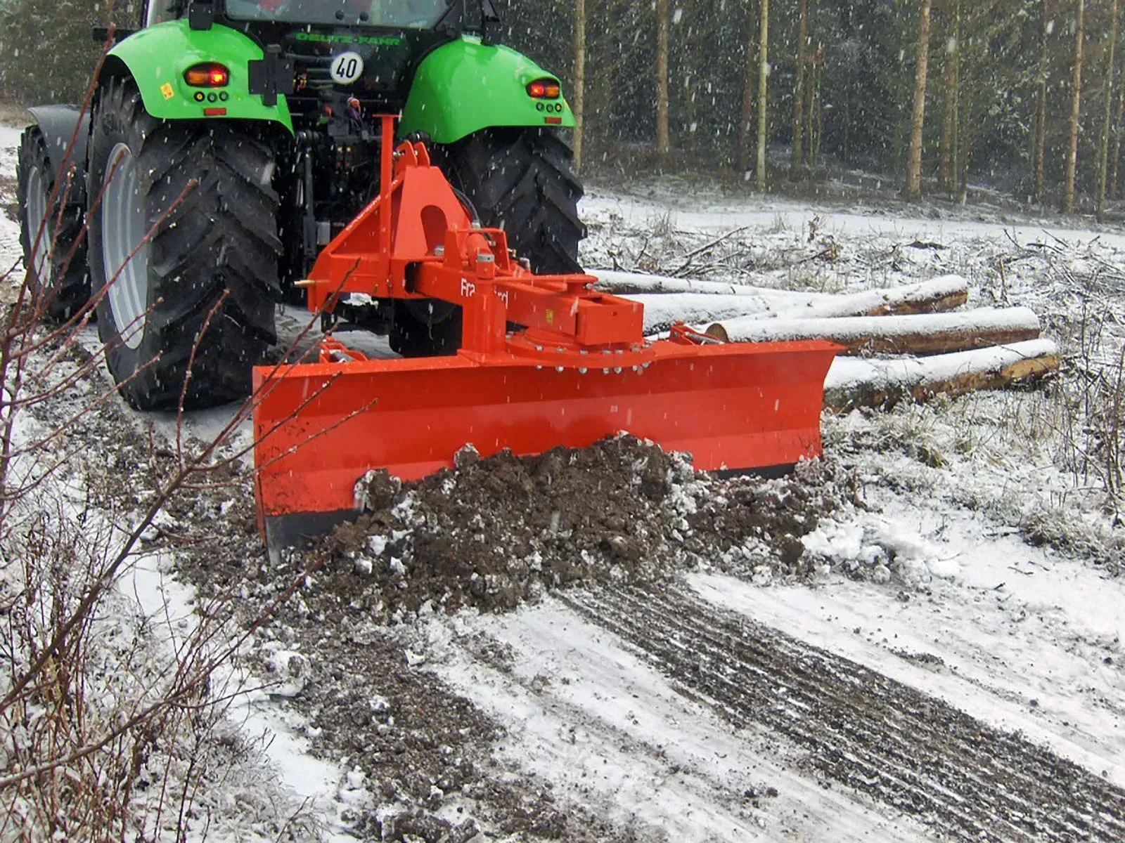 Ein grüner Traktor räumt eine verschneite Straße