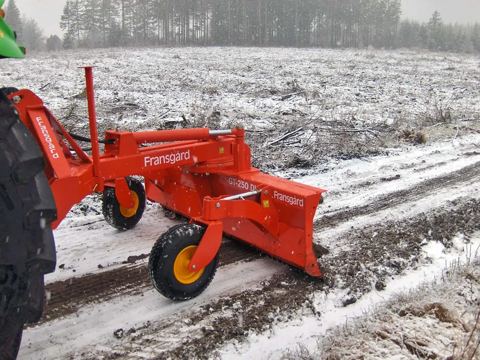 Ein roter Traktor steht auf einem schneebedeckten Feld