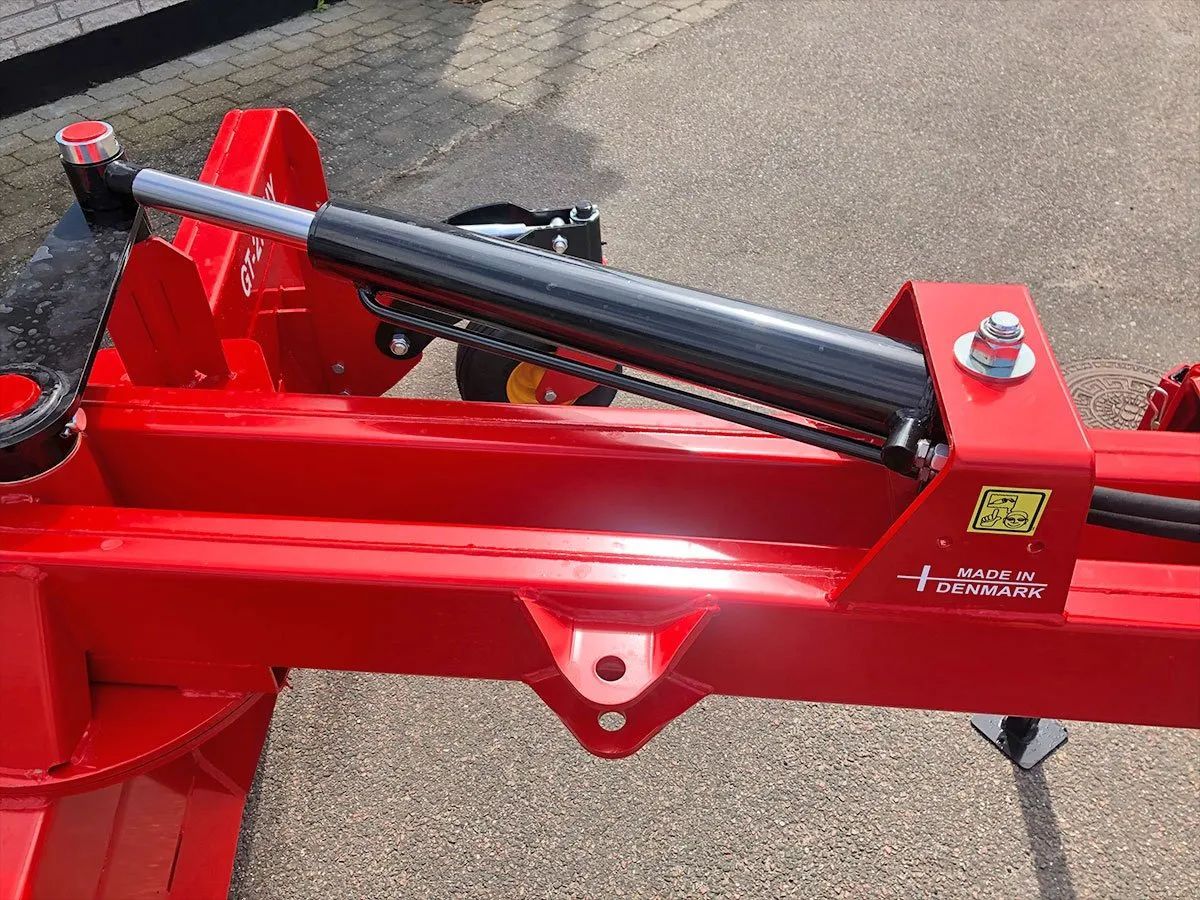 Eine Nahaufnahme einer roten Maschine mit einem Hydraulikzylinder.