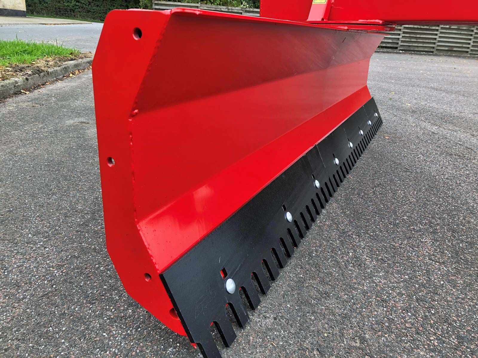 Am Straßenrand steht ein rot-schwarzer Pflug.