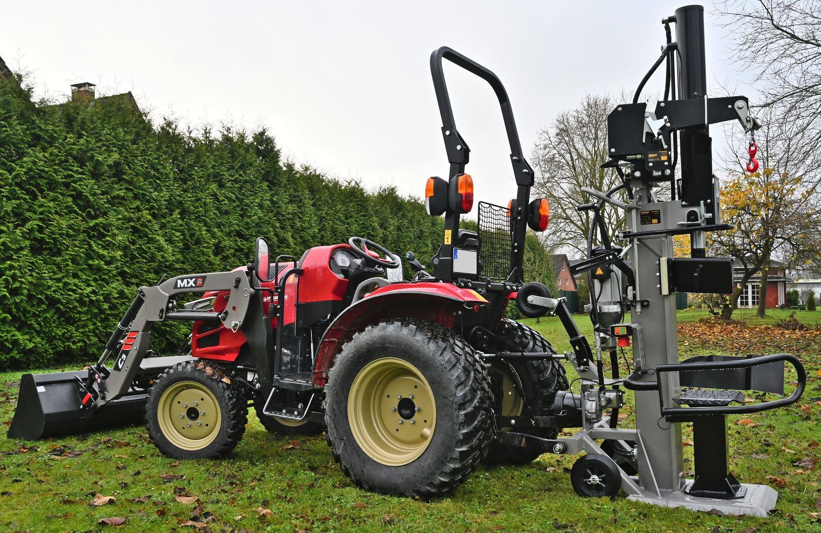 Ein roter Traktor steht am Rand einer unbefestigten Straße im Wald.