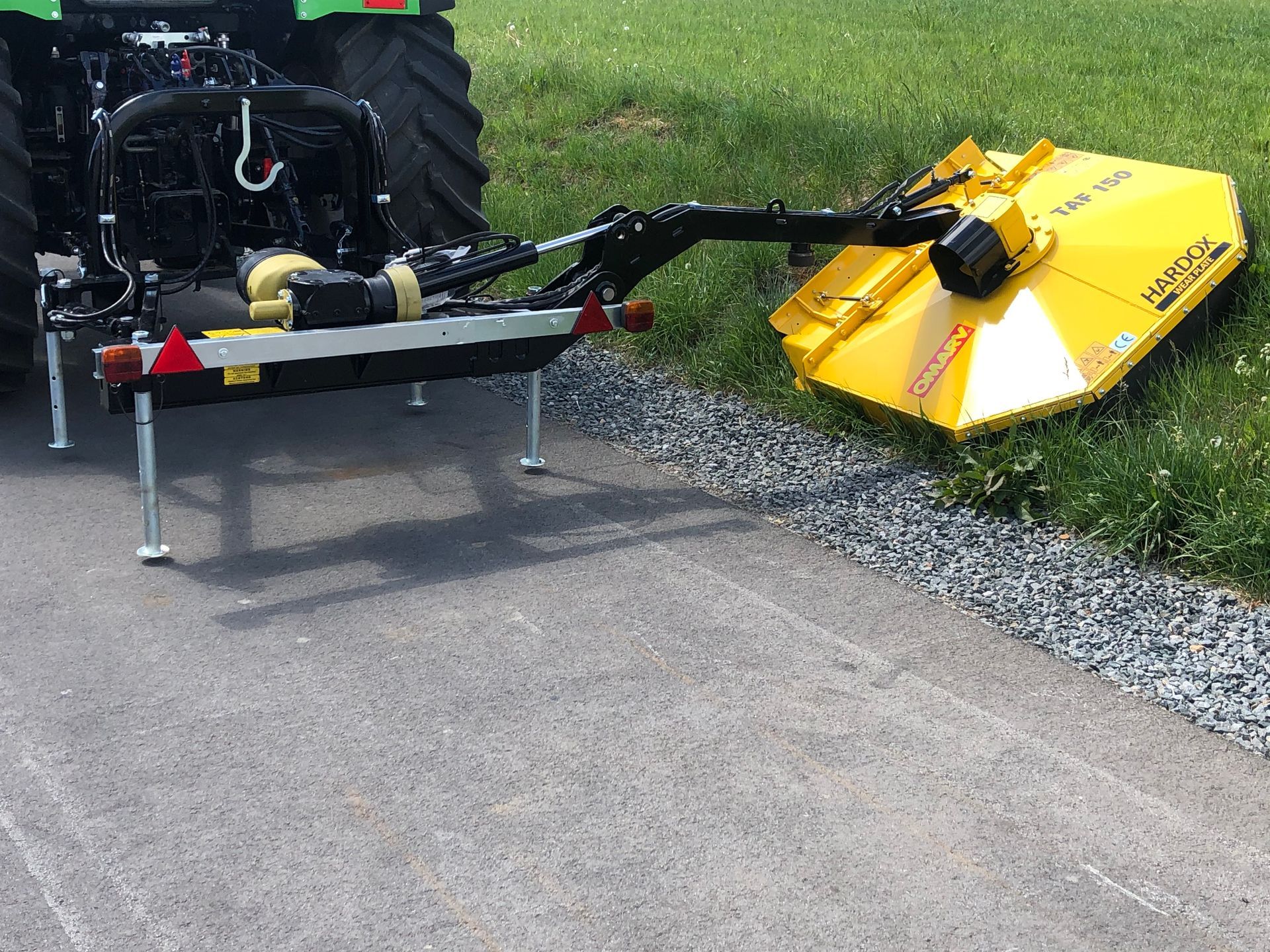 Ein gelber Rasenmäher ist an der Rückseite eines Traktors befestigt
