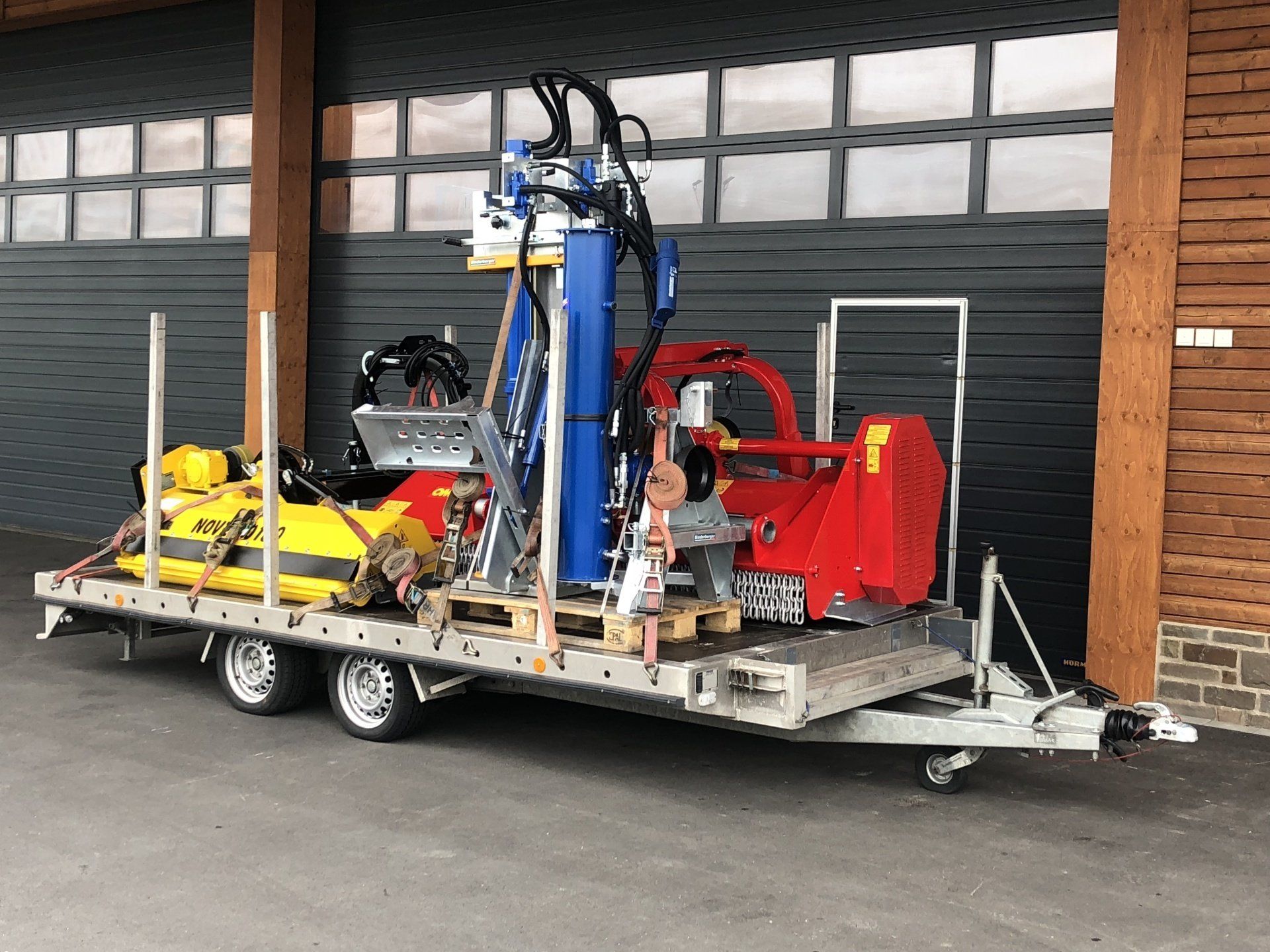 Vor einem Gebäude ist ein Anhänger mit vielen Maschinen geparkt.