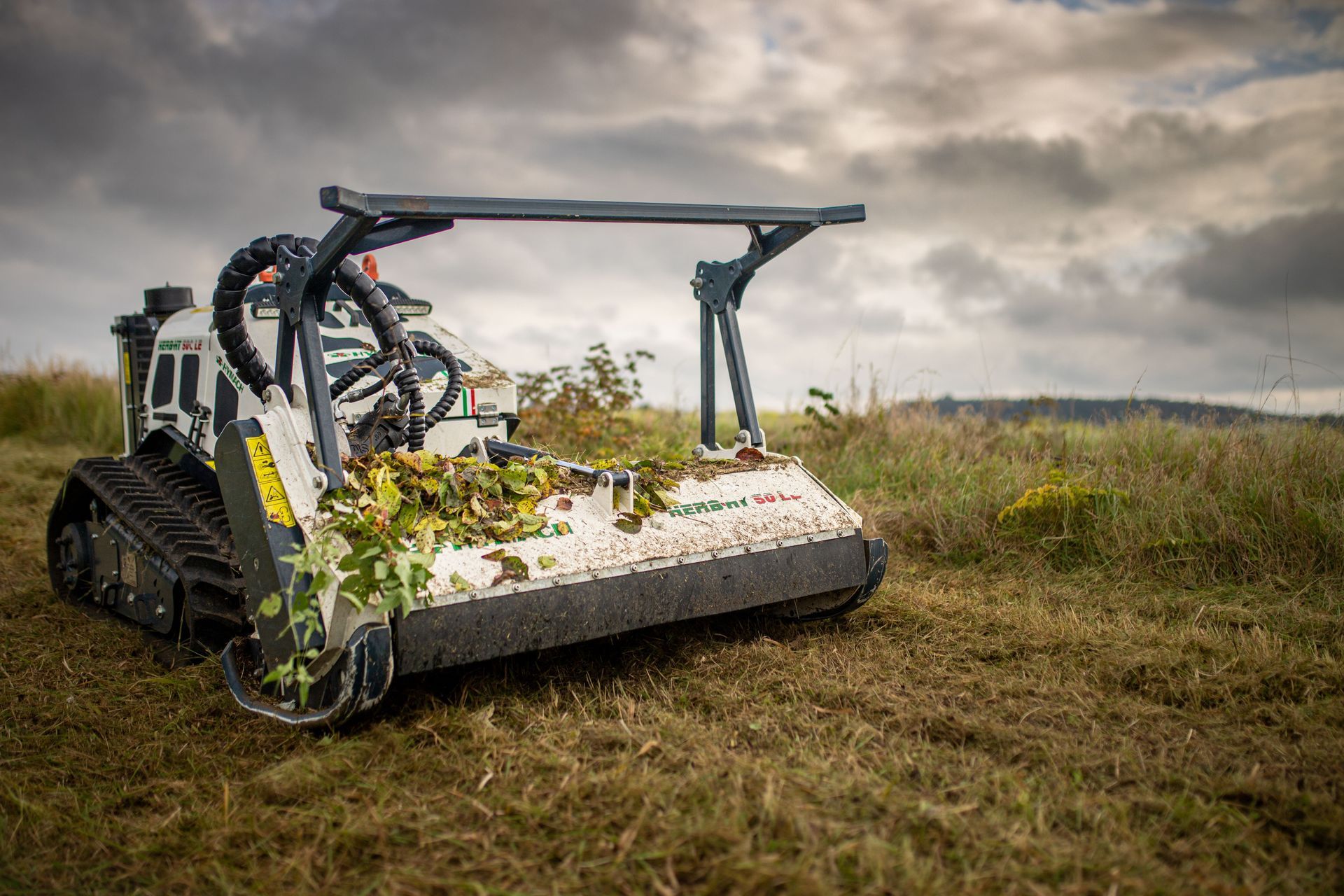 Ein kleiner Traktor schneidet Gras auf einem Feld.