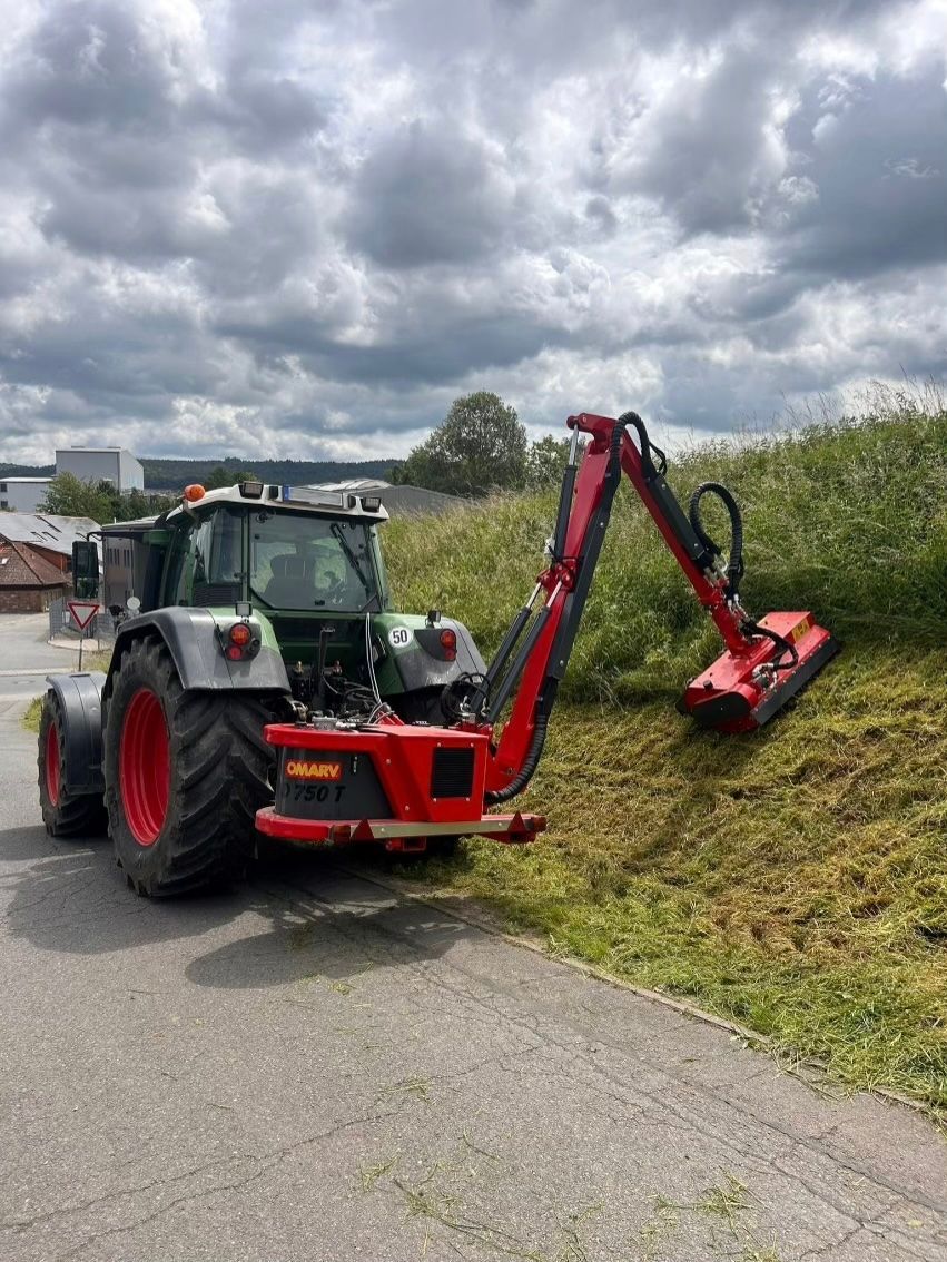 Ein Traktor schneidet Gras am Straßenrand.