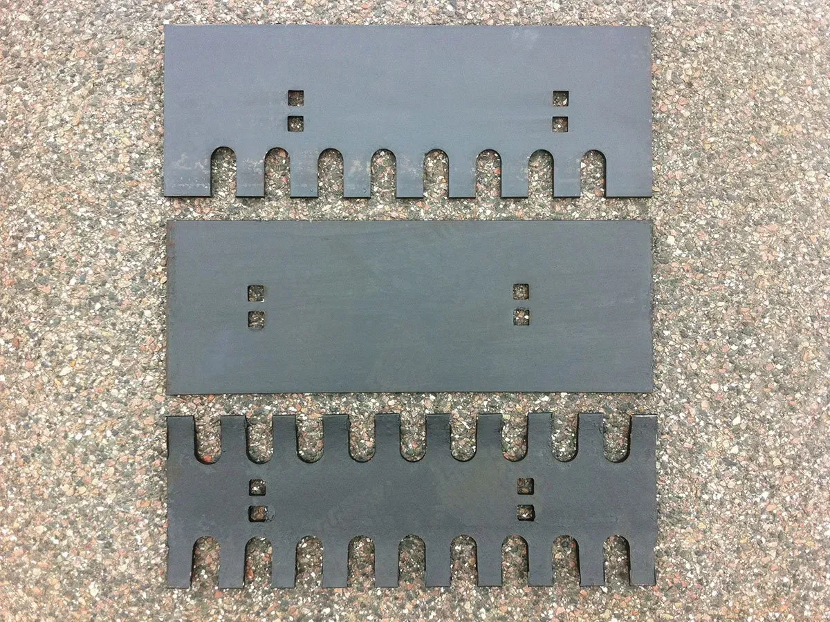 Zwei Metallstücke mit Löchern darin liegen auf einer Kiesfläche