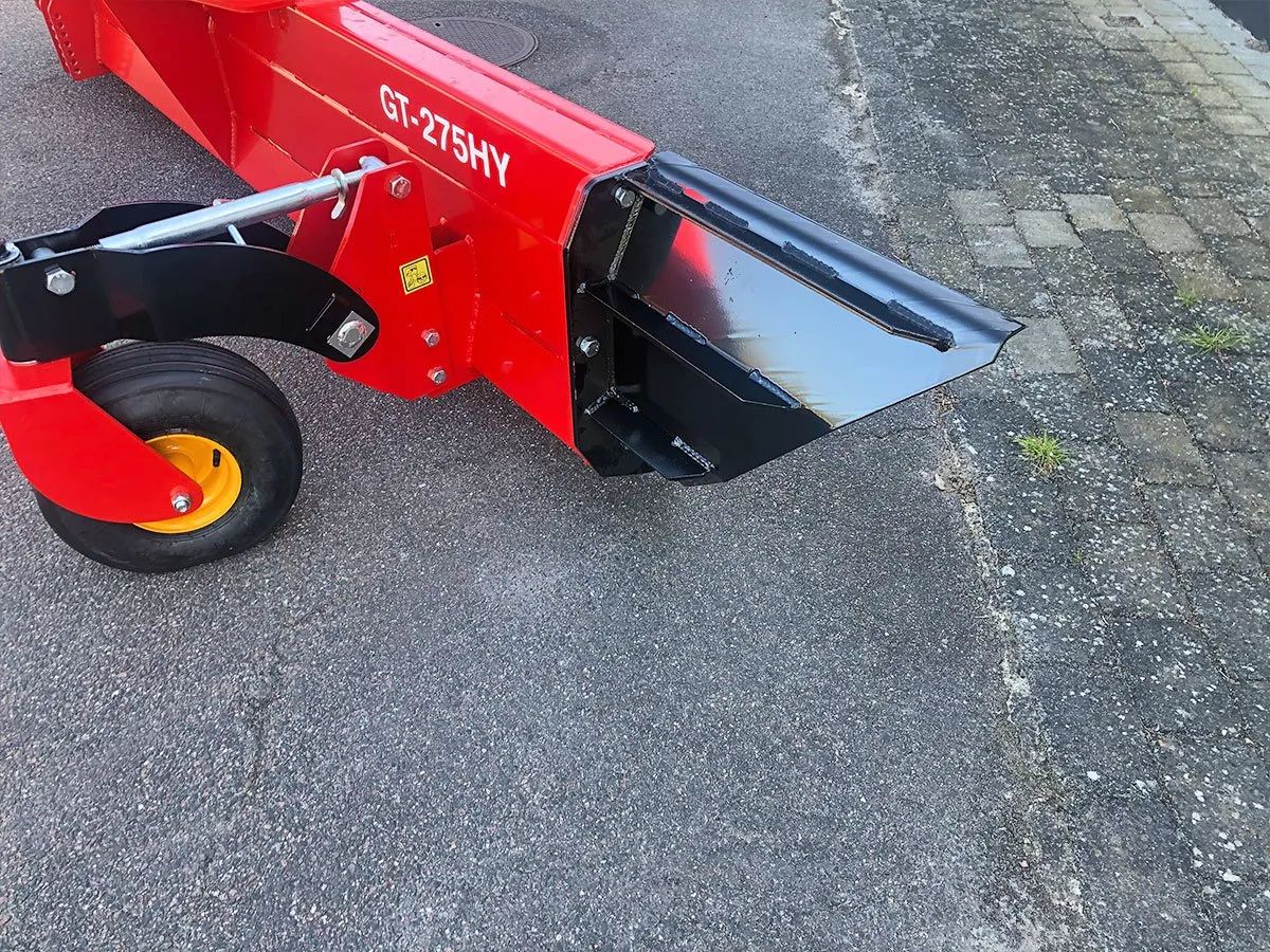 Ein rot-schwarzer Traktor steht am Straßenrand.