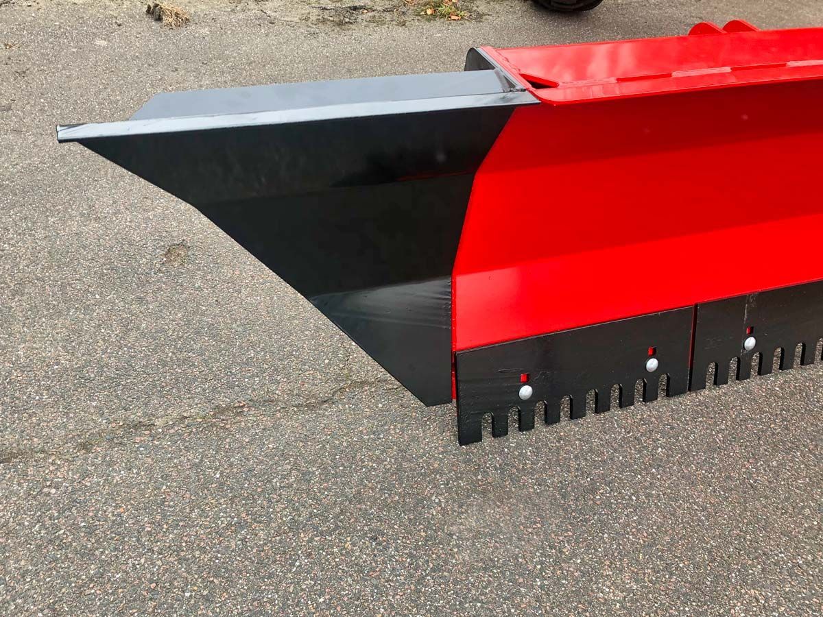 Auf dem Boden steht ein rot-schwarzer Schneepflug.