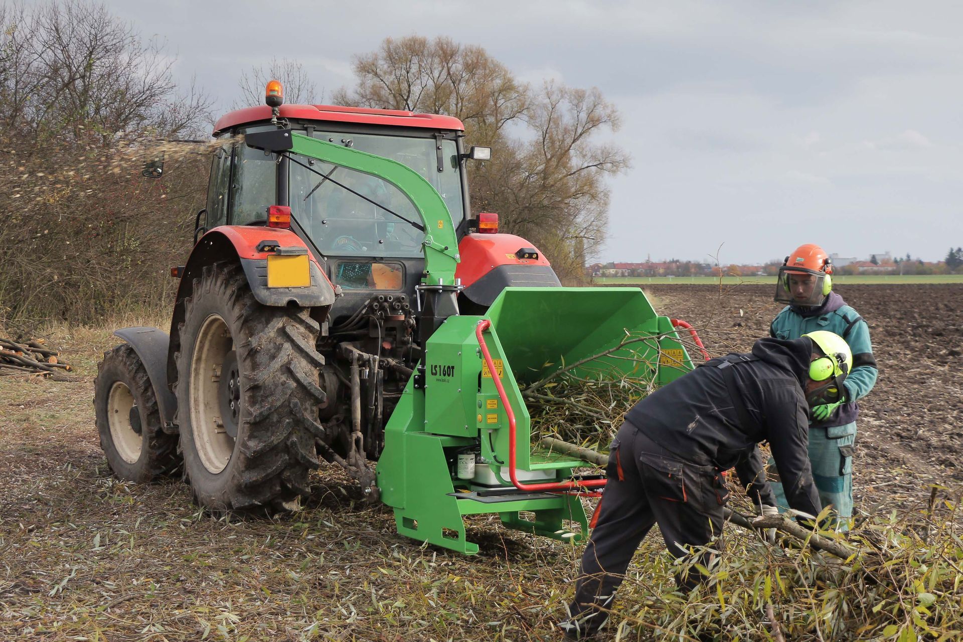Ein Mann steht neben einem grünen Traktor auf einem Feld.