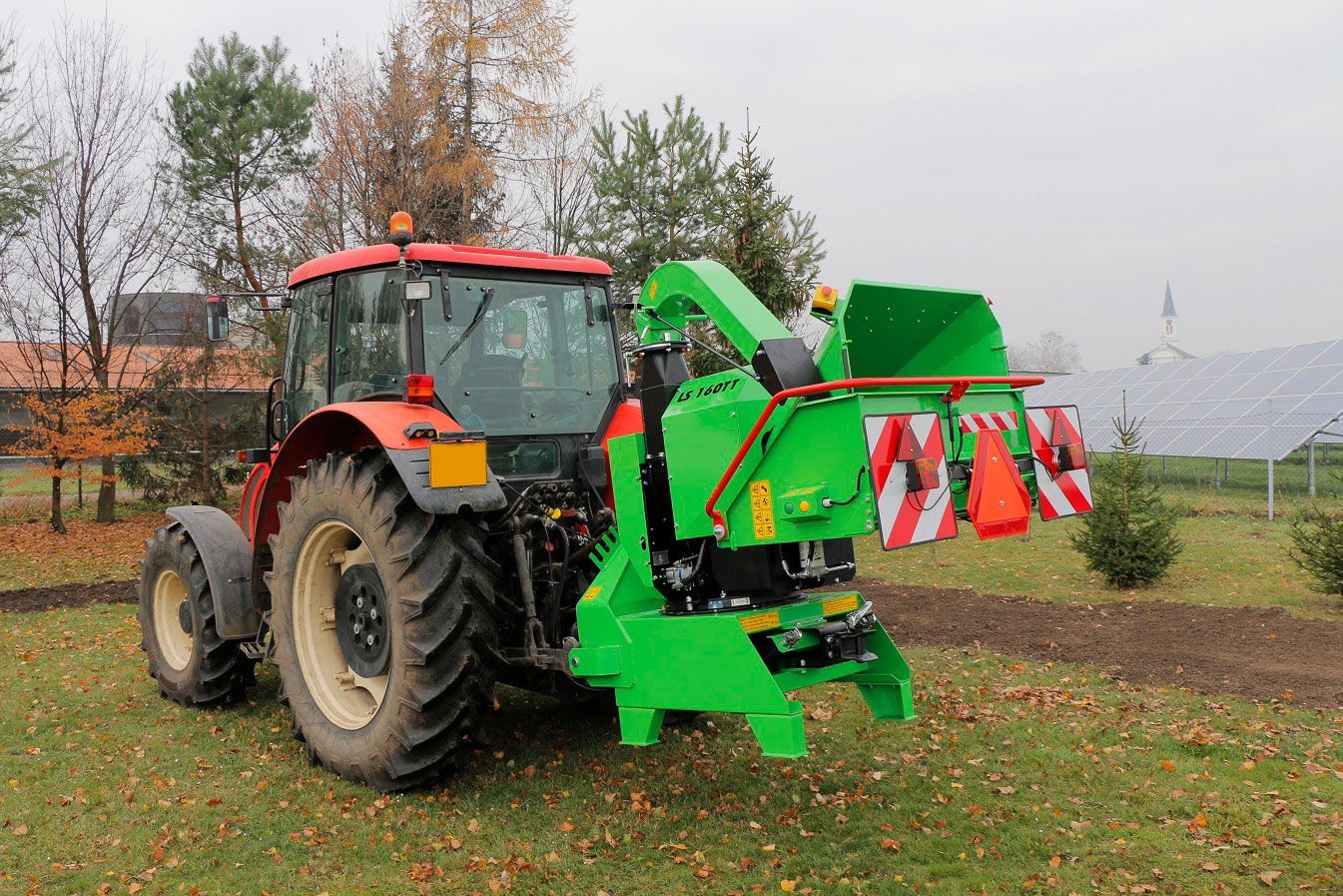 Auf einer Wiese steht ein Traktor mit einem daran montierten Grünhäcksler.