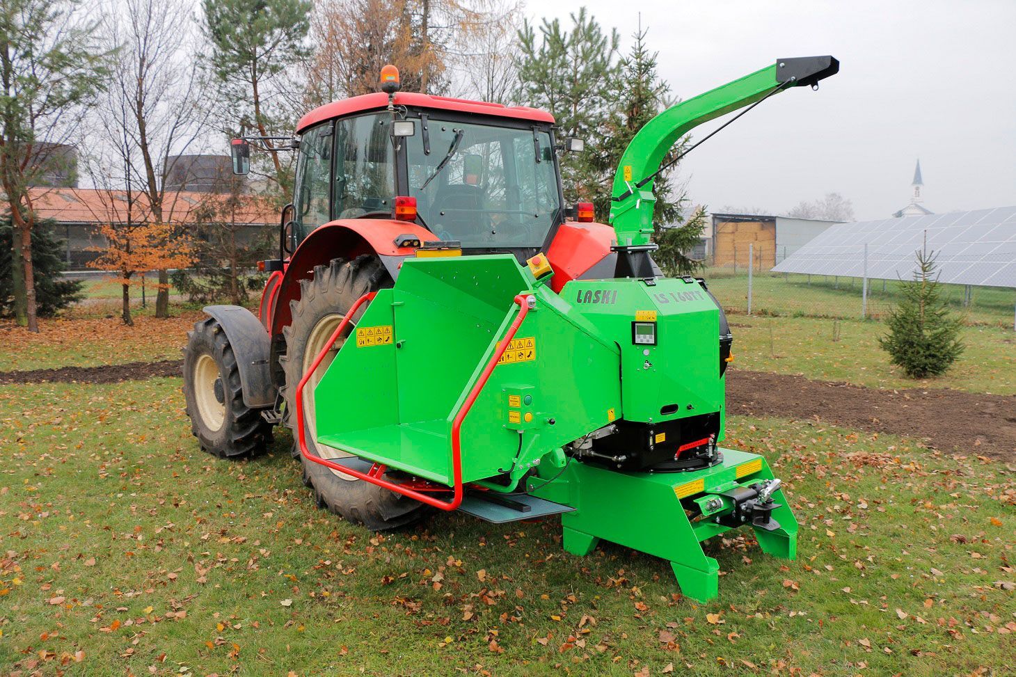 Ein grün-roter Traktor steht auf einer Wiese.
