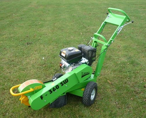 Ein grüner Baumstumpffräse liegt im Gras