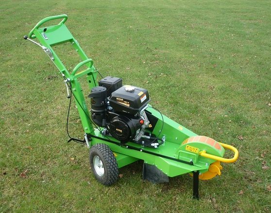 Ein grüner Rasenmäher mit einem schwarzen Motor steht auf einem üppigen grünen Feld.