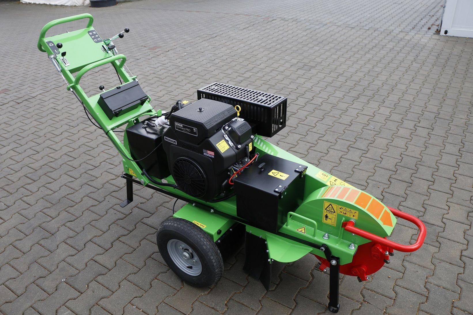 Eine grüne Maschine steht auf einem Ziegelsteinpflaster.