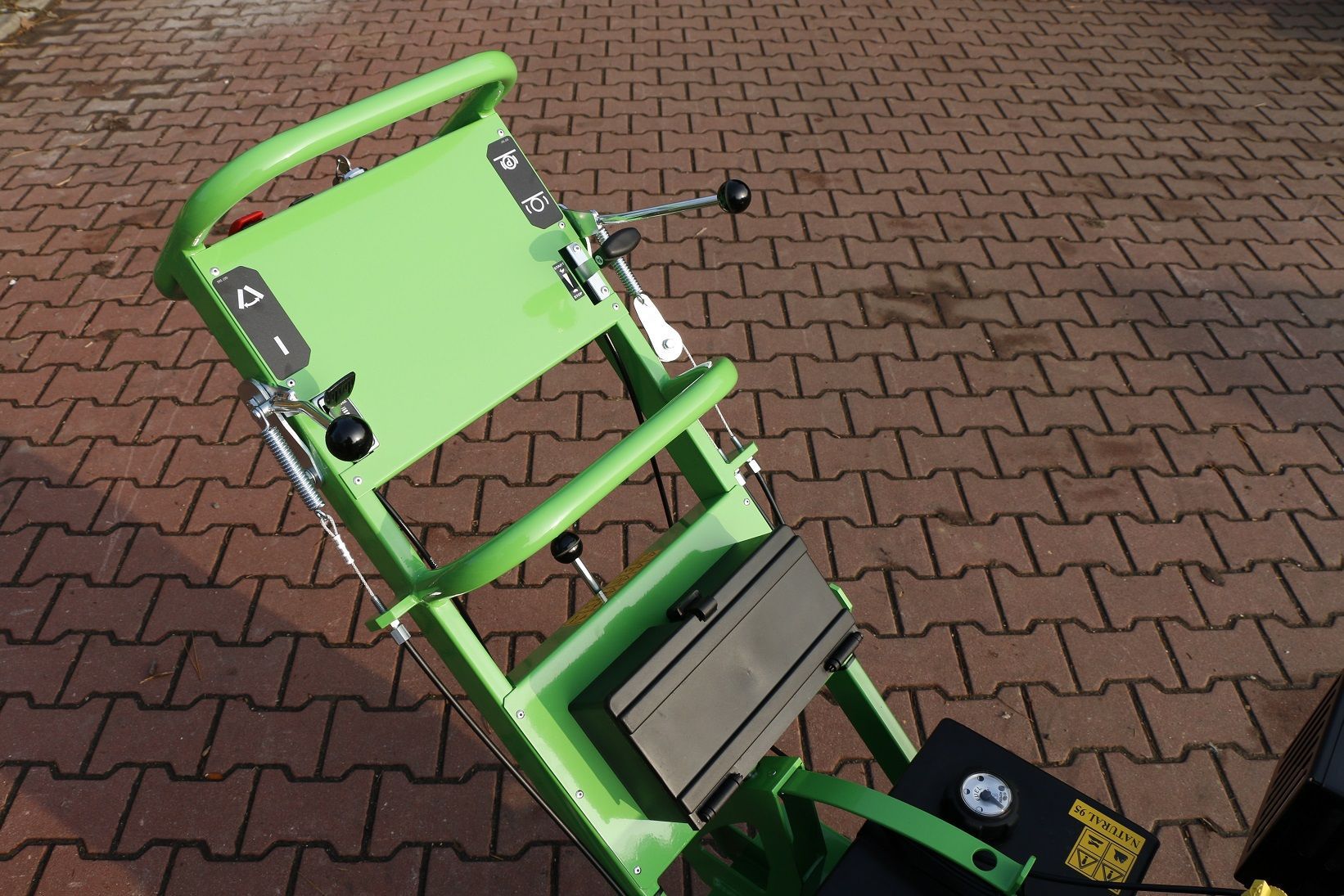 Ein grüner Rollstuhl steht auf einem Gehweg aus Backsteinen.