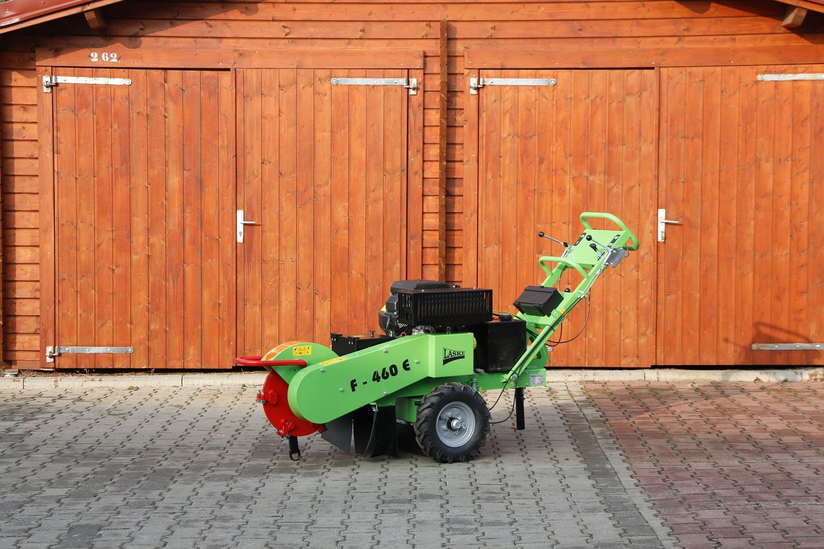 Eine grüne Maschine steht vor einem hölzernen Garagentor.