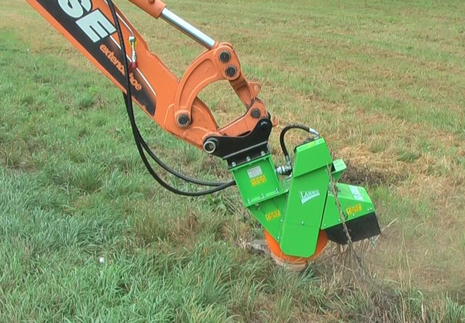 Eine grün-orangefarbene Maschine steht auf einem grasbedeckten Feld.