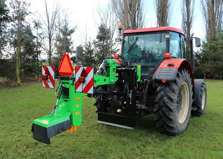 Ein grün-roter Traktor steht auf einer Wiese.