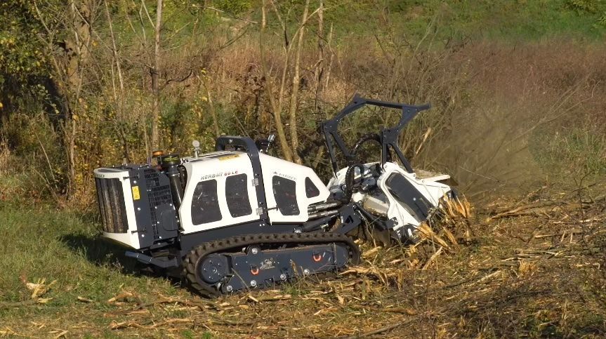 Ein schwarz-weißer Traktor schneidet Gras auf einem Feld.