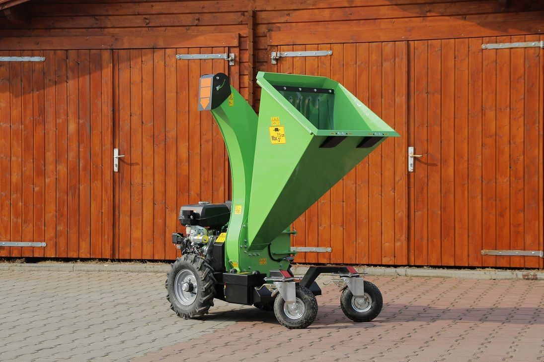 Eine grüne Maschine steht vor einer Holzgarage.