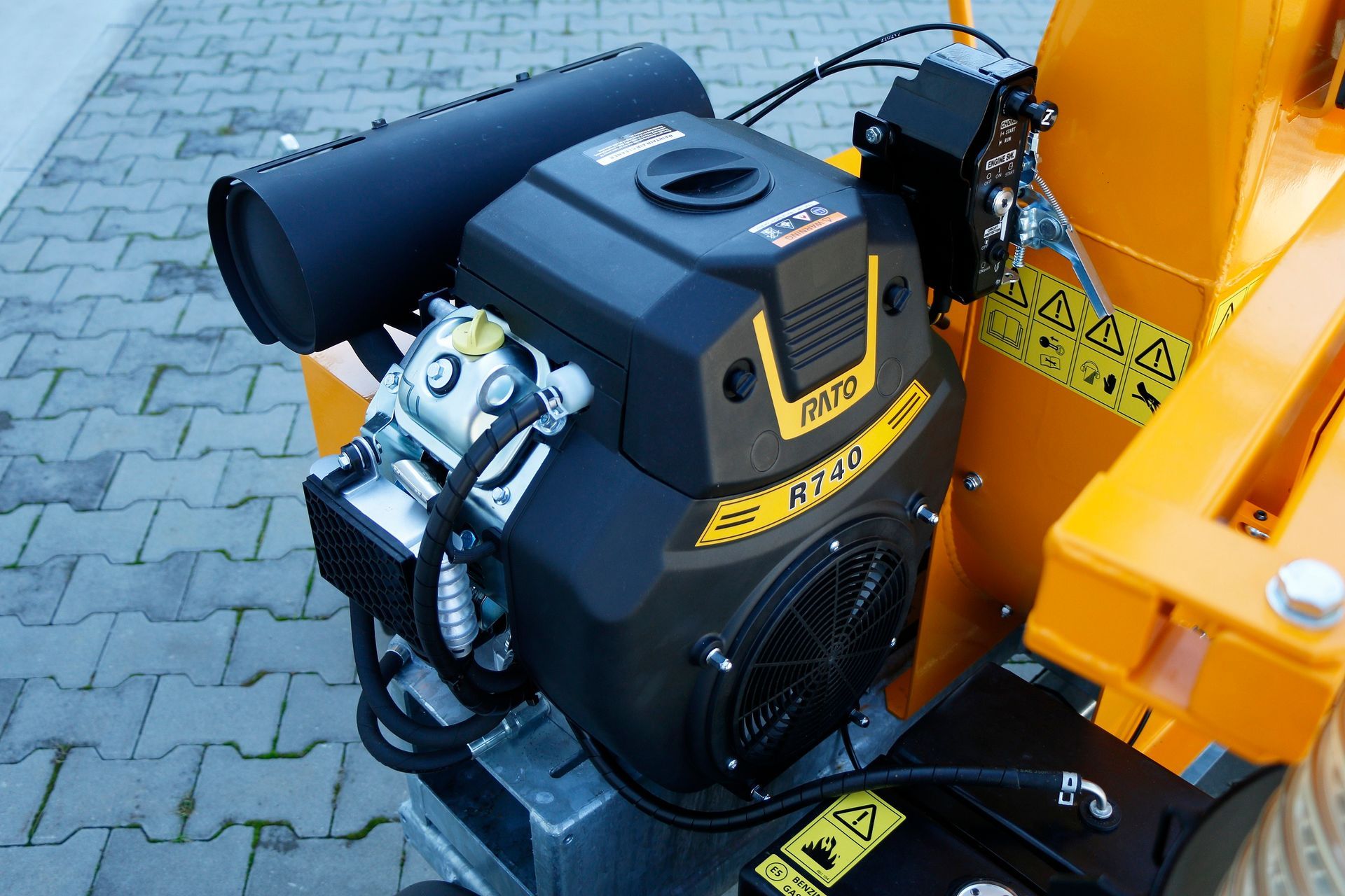 Eine schwarz-gelbe Lokomotive steht auf einem gepflasterten Gehweg