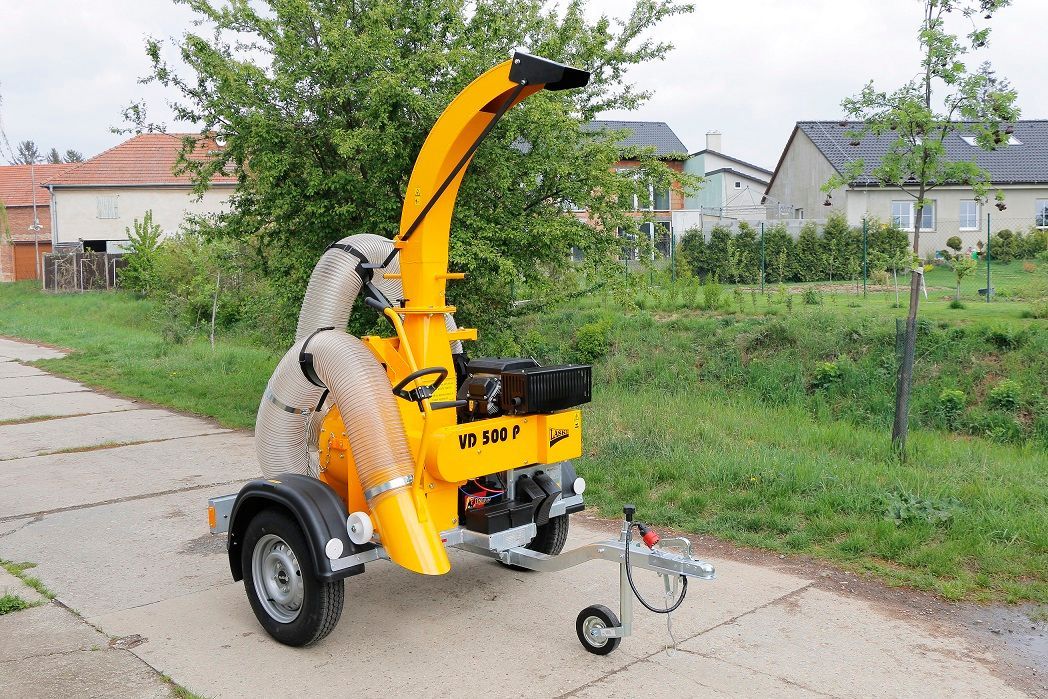 Am Straßenrand parkt ein gelber Baumhäcksler.