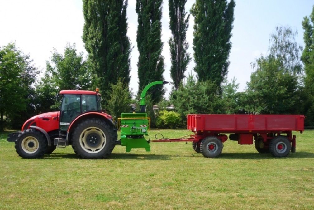 Ein roter Traktor zieht einen roten Anhänger auf einer Wiese