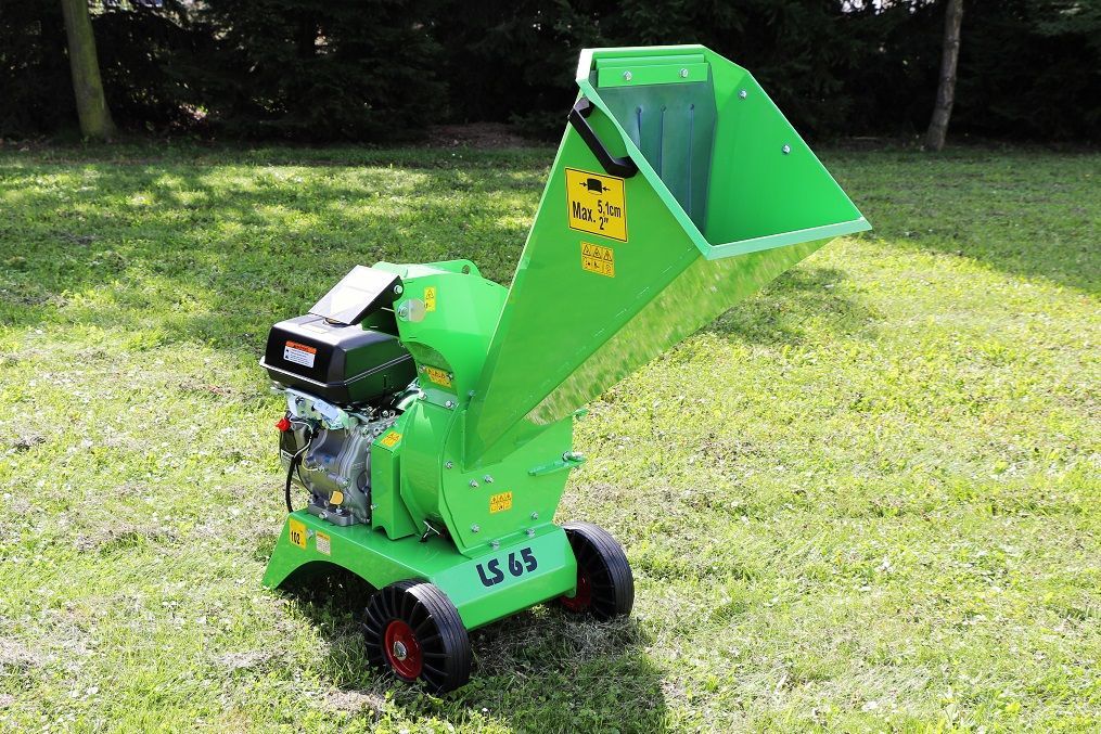 Ein grüner Holzhäcksler steht auf einem üppigen grünen Feld.